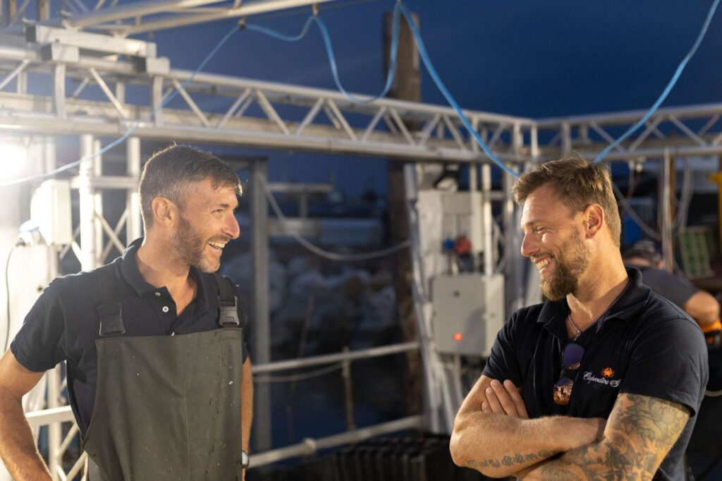 Due pescatori chiacchierano e ridono.